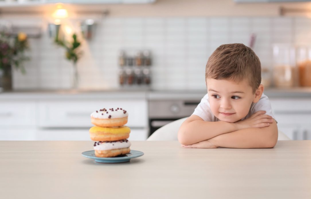 Enfant à table qui regarde des donut